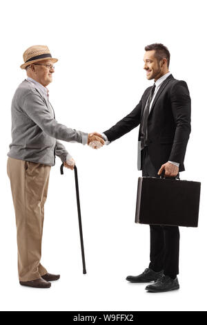 Lunghezza piena ripresa di profilo di un anziano gentiluomo stringono le mani con un giovane uomo in un vestito con una valigetta isolati su sfondo bianco Foto Stock