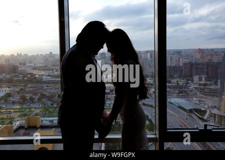 Silhouette di sposa bella giovane donna e lo sposo uomo bello condividere l'amore un testa a testa su sfondo della finestra . La sposa e lo sposo in una casa accogliente Foto Stock