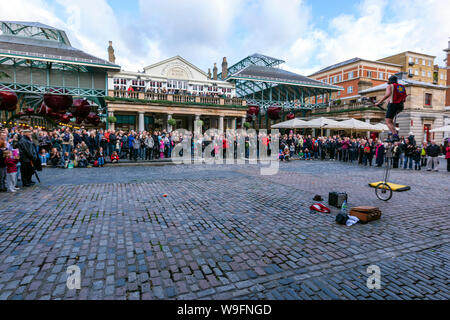 Street performer unicycles giocoleria in Covent Garden di Londra, Inghilterra, Regno Unito Foto Stock