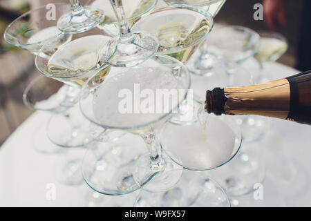 La piramide di bicchieri di vino con champagne . Lo champagne è versata in bicchieri. Decorazione di festa della manifestazione con una piramide di bicchieri di champagne Foto Stock