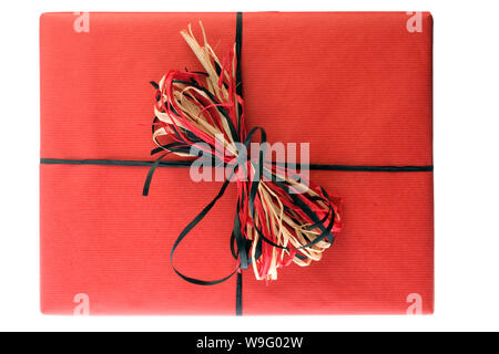 Un regalo in formato carta di colore rosso con una raffia bow isolato su uno sfondo bianco Foto Stock