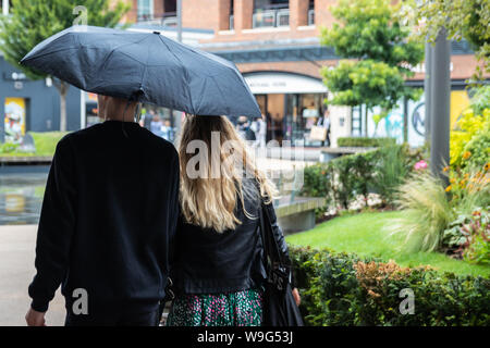 Un paio di camminare insieme sotto un ombrello sotto la pioggia Foto Stock