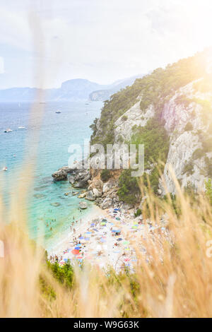(Fuoco selettivo) vista da sopra, splendida vista di una bellissima spiaggia piena di ombrelloni da spiaggia e la gente a prendere il sole e nuotare in un'acqua turchese. Foto Stock