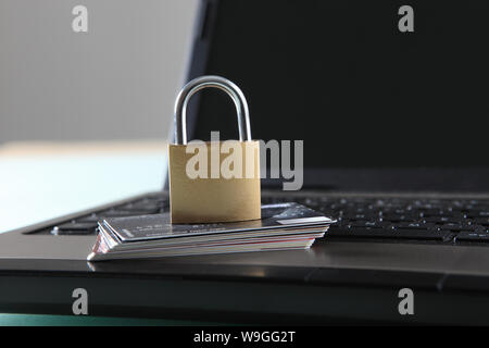 Lock and stack of credit cards on top of laptop Stock Photo