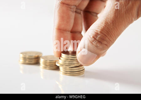 Persona mano che dispone le monete nella forma di grafico a barre Foto Stock