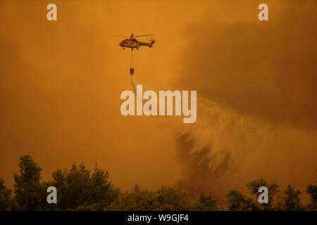 (190814) -- Pechino, 14 agosto 2019 (Xinhua) -- un acqua-la caduta di un elicottero è visto combattendo un wildfire Makrymalli vicino villaggio sull isola di Eubea, Grecia, Agosto 13, 2019. Il greco i vigili del fuoco sono state combattendo la più grande di incendi di questa estate che infuria in due grandi fronti vicino ad Atene il martedì, le autorità locali ha detto. Più di 500 residenti sono stati evacuati da tre villaggi come una misura precauzionale e feriti sono stati segnalati né nei pressi di Tebe città del continente, a nord-ovest della capitale, né sulla isola di Eubea, due ore di auto da Atene, secondo il servizio antincendio. (Foto da n. Foto Stock