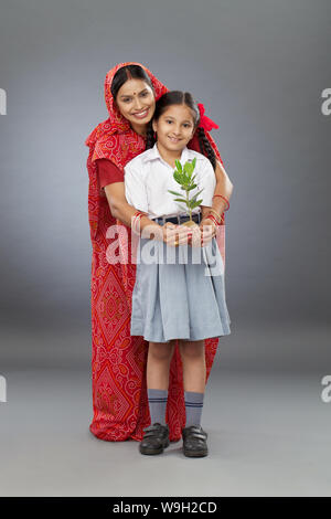 Madre con la figlia che tiene una piccola pianta Foto Stock