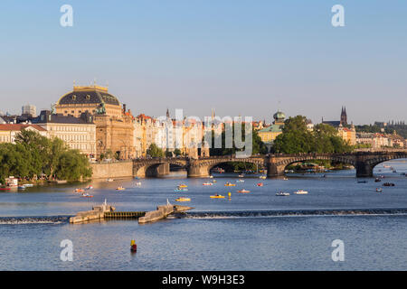 Vista la Legione Bridge, il Teatro Nazionale e di altri vecchi edifici e persone su barche a pedali sul fiume Moldava a Praga, Repubblica Ceca. Foto Stock