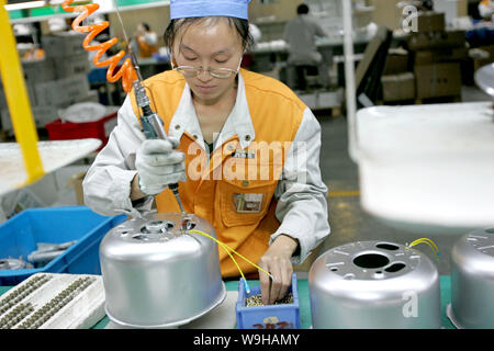 La foto del file del 25 ottobre 2005 mostra i lavoratori cinesi che fanno i ruscelli elettrici di riso nella fabbrica di Zhejiang Supor Electrical Appliances Manufacturin Foto Stock