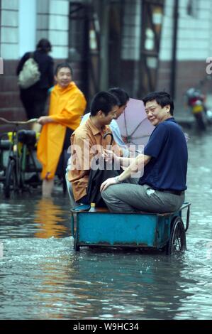 I residenti locali prendere un triciclo su strade allagate nella città di Xiangfan, porcellane centrale provincia di Hubei 14 luglio 2007. Più di 400 persone sono state kill Foto Stock