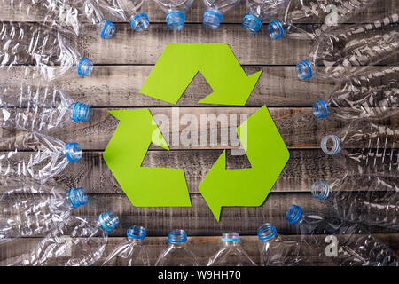 Telaio di bottiglie di plastica usate con simbolo di riciclaggio su sfondo di legno. Concetto di riciclo Foto Stock