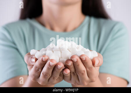 Close up donna bella mani tenendo lo zucchero bianco i cubi. Il concetto di assistenza sanitaria. Foto Stock