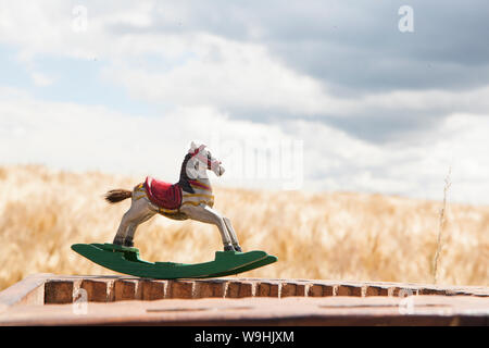 Mobili d'antiquariato in legno miniaturizzati a cavallo a dondolo in un campo di grano Foto Stock