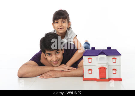 Father and daughter lying on floor with dream home Stock Photo