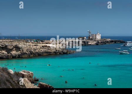 Favignana, Italia - 09 agosto 2019: la famosa Cala Azzurra beach e la Punta Marsala faro nella bellissima isola di Favignana, Sicilia. Foto Stock