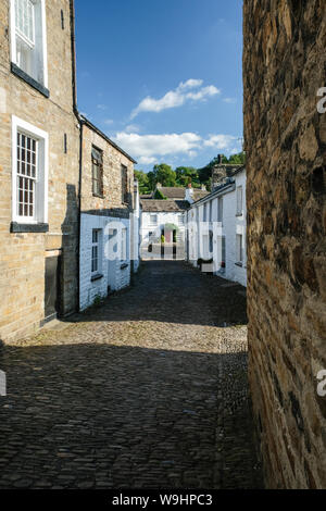 Una strada di ammaccatura, il piccolo villaggio di Dentdale, Cumbria, entro le Yorkshire Dales National Park Foto Stock