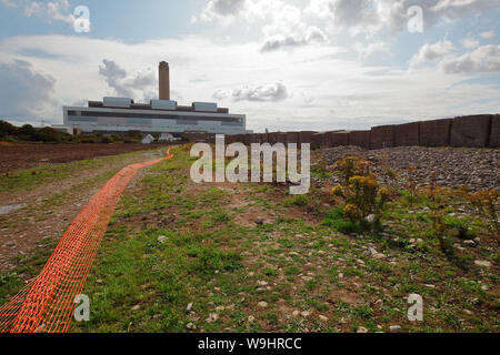 Con il generatore di enorme hall di Aberthaw power station in background e una fila di enormi blocchi di calcestruzzo di rivestimento per le spiaggia gli sbarchi di arresto. Foto Stock