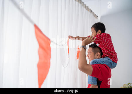 Famiglia decorare la loro casa con bandiera indonesiana Foto Stock