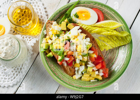 Avodaco insalata di uova con pomodori ciliegia servito su toast con la maionese fatta in casa salsa bianca sul tavolo rustico Foto Stock