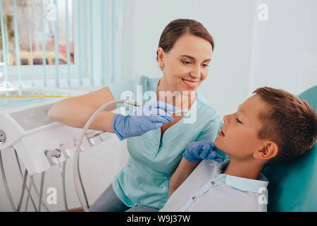 Carino Ragazzo che sorride mentre i denti esame . Felice ragazzo seduto nella sedia dentisti e avente check up denti Foto Stock