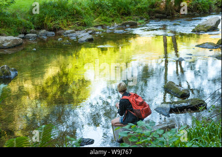 Giovane fotografo con lo smartphone nelle fasi Tarr riserva nazionale, Exmoor, REGNO UNITO Foto Stock