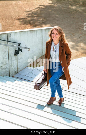 Ragazza porta violino in mani e salite le scale Foto Stock