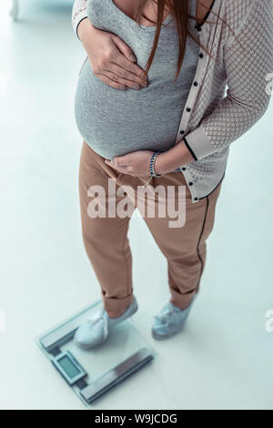 Giovani femmine gravide di persona in piedi sui pesi Foto Stock