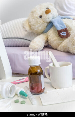 L'influenza stagionale concetto, ill kid ragazza con con le pillole medicinali, termometro. Nella stanza dei bambini nel letto con i giocattoli di peluche spazio copia Foto Stock