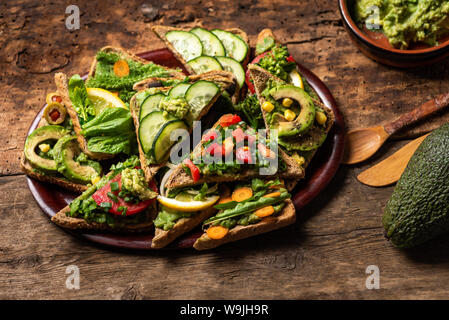 Sandwich vegetariano con il guacamole e le verdure su una superficie di legno Foto Stock