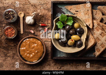 Verde e olive nere e altri stuzzichini sul tavolo di legno Foto Stock