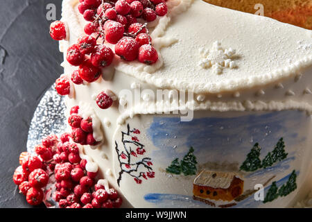 Inverno torta ricoperta di glassa bianca, con casa dipinta nella foresta, alberi e rosso rowan. Foto Stock