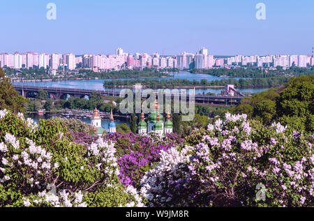 Chiesa del paesaggio sullo sfondo del fiume Dnieper e la grande città di Kiev, circondato da lillà in fiore, vista dal giardino Foto Stock