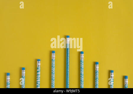 Teal blu e bianco matite modellato eraser Fine in alto lungo il fondo su un brillante sfondo giallo con spazio di copia Foto Stock