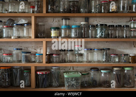 Righe di vetro riciclato vasetti contenitori utilizzati per memorizzare diverse dimensioni di viti, chiodi, barche, rondelle, dadi in modo organizzato Foto Stock