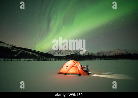 Fotografo in una tenda illuminata da luci del nord (aurora boreale e il cielo stellato di notte polare, Svensby, Alpi Lyngen, Troms, Norvegia e Scandinavia Foto Stock