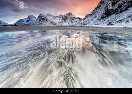 Tramonto sul Skagsanden surreale spiaggia circondata da montagne coperte di neve, Flakstad, Isole Lofoten artico, Norvegia, Scandinavia, Europa Foto Stock