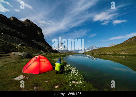 Escursionista accanto alla tenda guardando verso il Cervino dal lago Riffelsee, Zermatt, canton Vallese, alpi svizzere, Svizzera, Europa Foto Stock