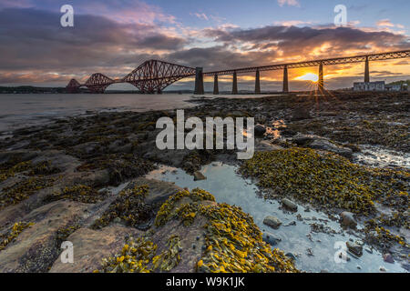 Sunrise attraverso il Ponte di Forth Rail, Sito Patrimonio Mondiale dell'UNESCO, sul Firth of Forth, South Queensferry, Edimburgo, Lothian, Scozia, Regno Unito Foto Stock