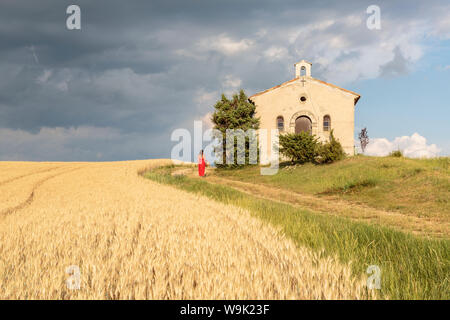 Donna in abito rosso e cesto di vimini passando da Notre-Dame-de-Sante cappella, Entrevennes, Alpes-de-Haute-Provence, Provenza Alpi Costa Azzurra, Francia Foto Stock