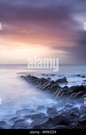 Tramonto su una tempesta del giorno guardando attraverso Kimmeridge Bay da resti di Clavell è Pier, Kimmeridge, vicino a Swanage, Dorset, England, Regno Unito Foto Stock