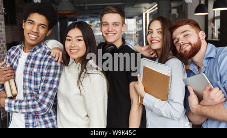 Felice schoolmates in posa insieme sorridente in telecamera Foto Stock