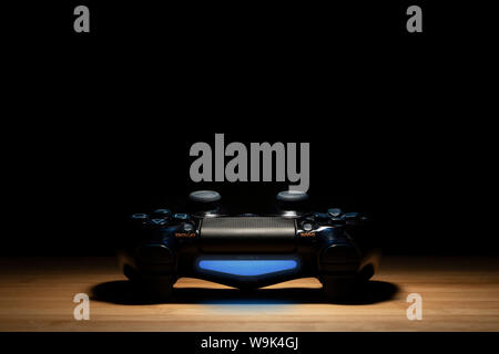 Brecht, Belgio - 10 agosto 2019: Un ritratto di una girata su Sony Playstation 4 controller sotto i riflettori con il buio intorno ad esso. PS4 controller Foto Stock