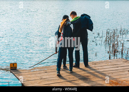 Il padre e la madre con bambino kid giocando con il bancale in prossimità di acqua. riverside Foto Stock