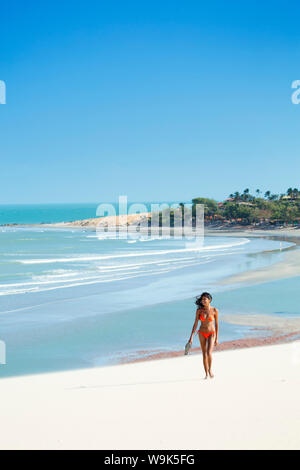 Una giovane donna a piedi lungo la spiaggia di Jericoacoara, Ceara, Brasile, Sud America Foto Stock