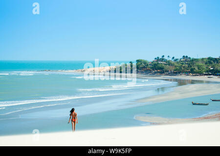 Una giovane donna a piedi lungo la spiaggia di Jericoacoara, Ceara, Brasile, Sud America Foto Stock