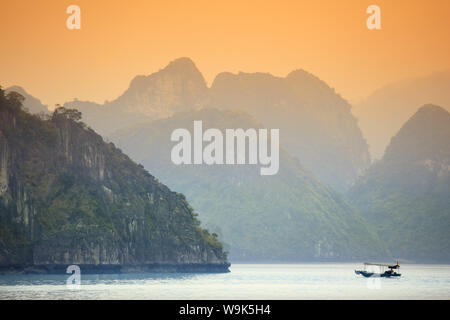 Barca sulla baia di Halong al tramonto, Sito Patrimonio Mondiale dell'UNESCO, Vietnam, Indocina, Asia sud-orientale, Asia Foto Stock