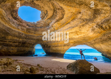 Un turista all'interno di grotte marine del a Benagil ammira le limpide acque dell'Oceano Atlantico, distretto di Faro, Algarve, Portogallo, Europa Foto Stock