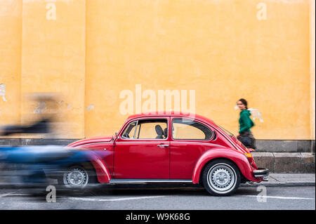 Una donna camminare davanti a un rosso VW Beetle in colorate strade di Popayan, Colombia, Sud America Foto Stock