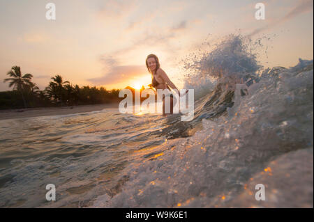 Una ragazza riproduce le onde a Palomino sulla costa caraibica della Colombia, Sud America Foto Stock