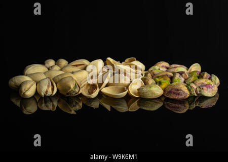 Sacco di tutto il lotto di pezzi di ripe pistacchio verde isolato sul vetro nero Foto Stock